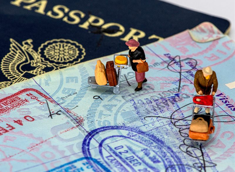 Passport with visa stamps and miniature travellers