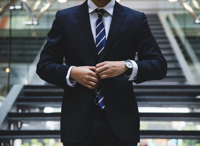Businessman in a navy suit adjusting his jacket